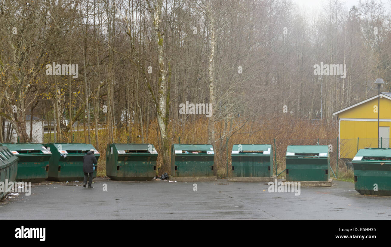 FLODA, SWEDEN - NOVEMBER 21 2018: Female person walking up to recycling container at public outdoor recycling centre Stock Photo