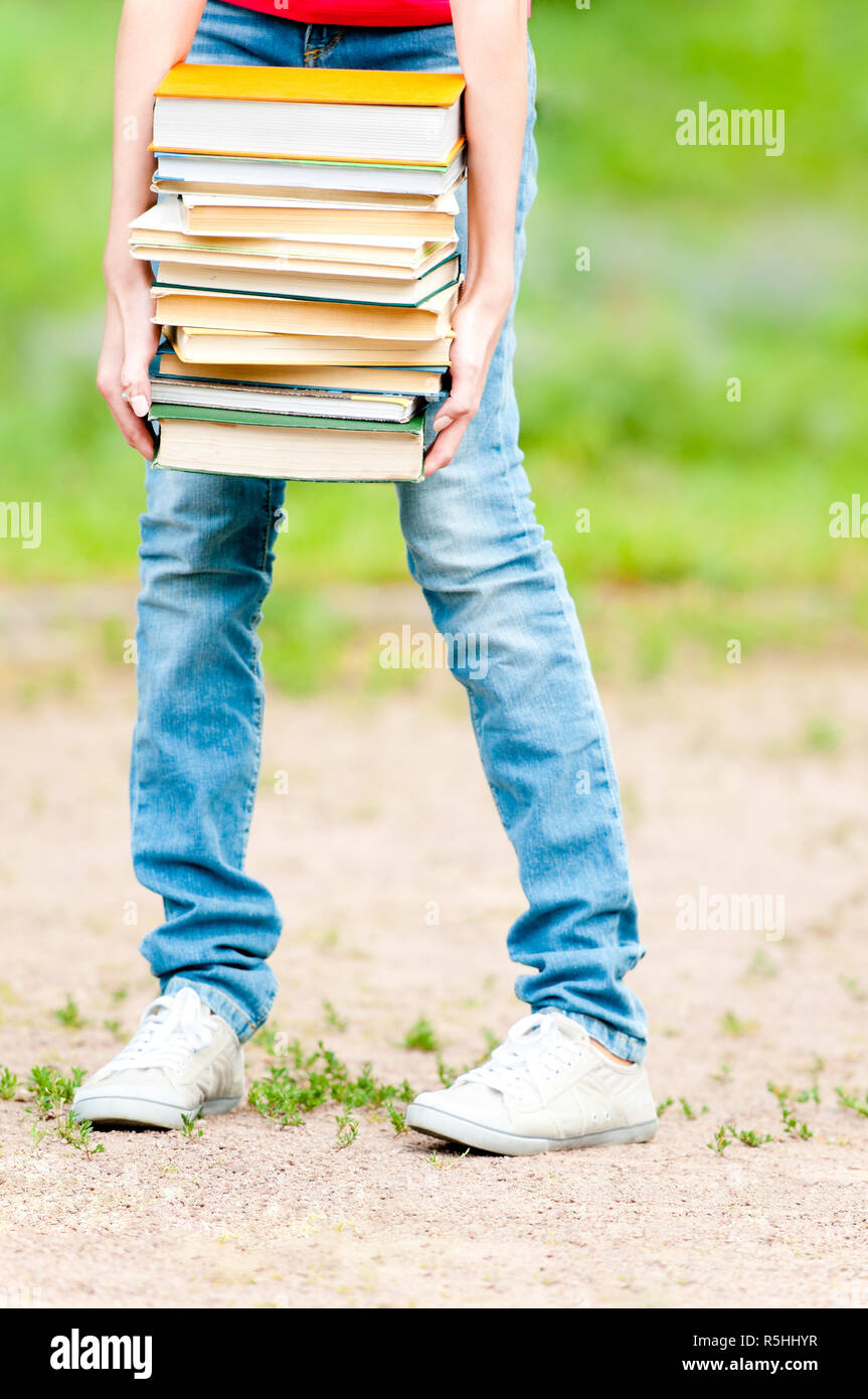 student girl holding big pile of heavy books Stock Photo - Alamy