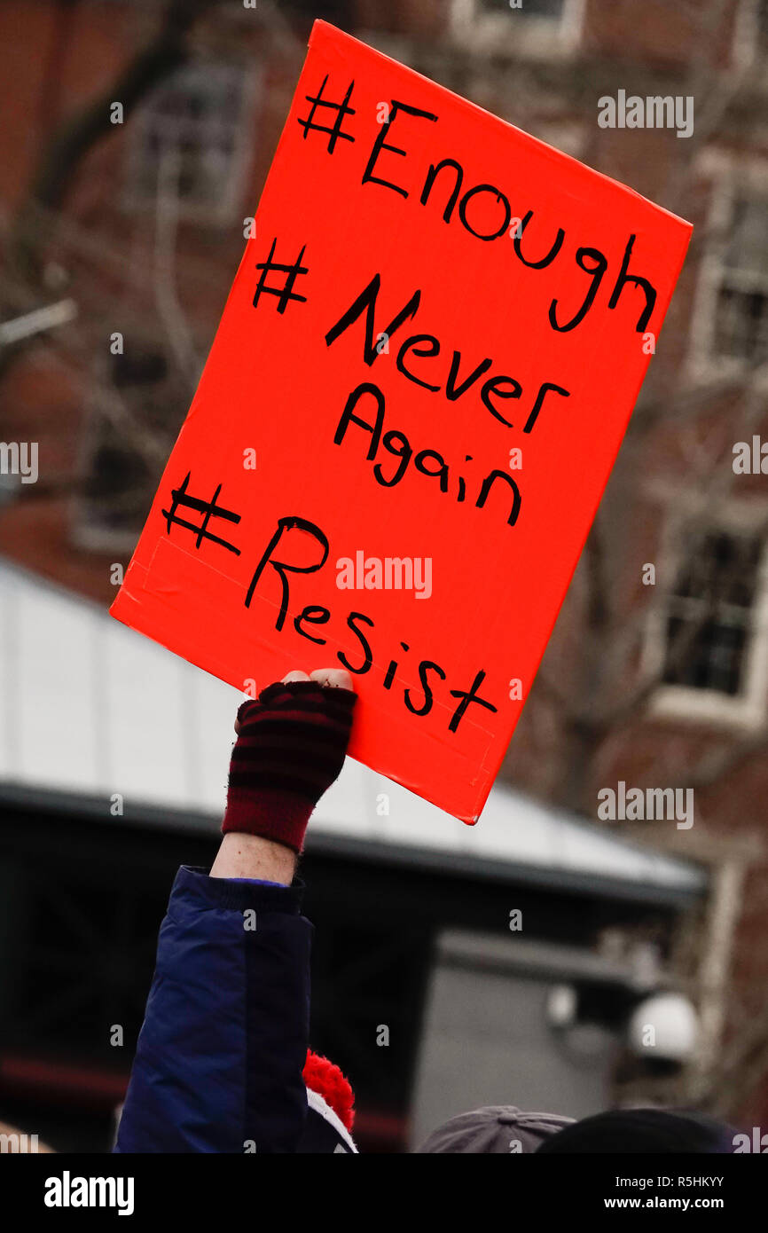 Protestor with a gloved hand holding a handwritten sign with several political slogans at a protest rally Stock Photo