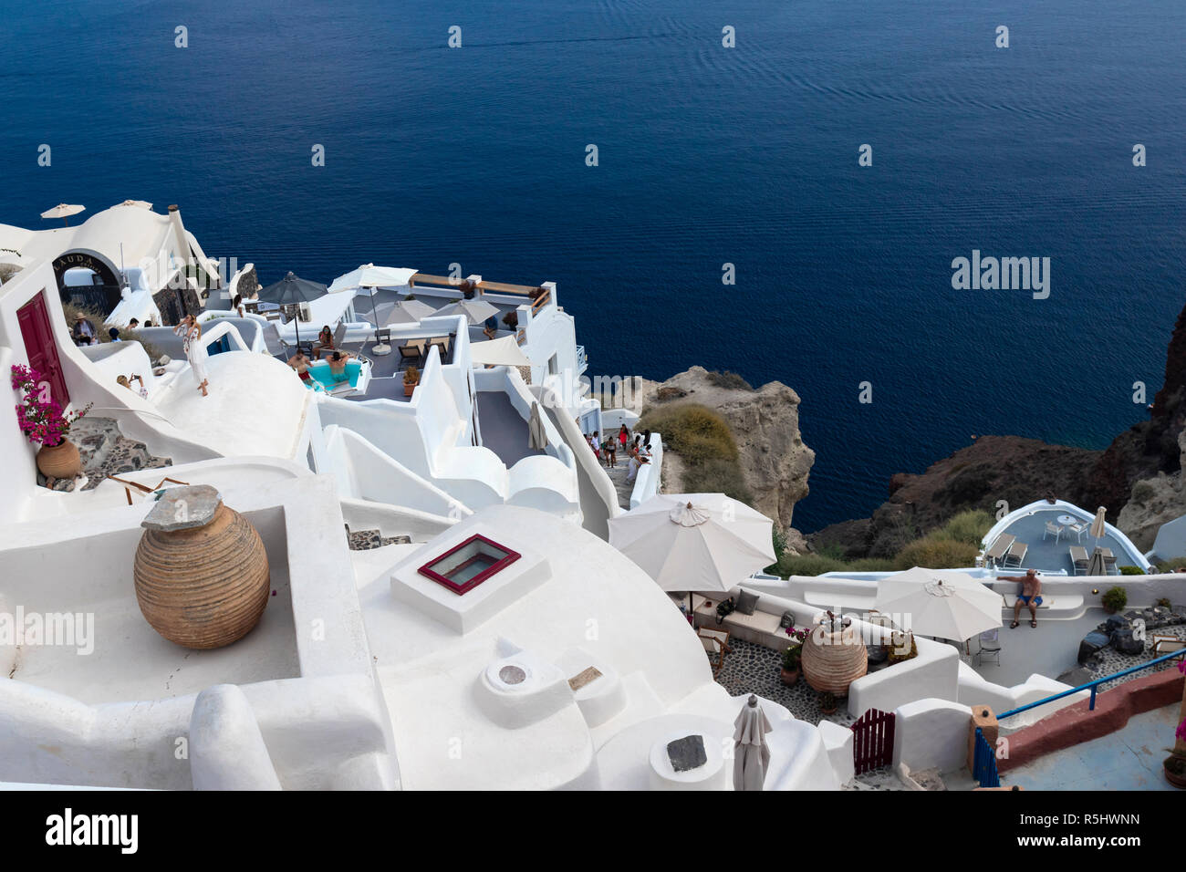 OIA, SANTORINI, GREECE - August 20, 2018: Wealthy tourists enjoy the sunshine at the pools in the exclusive cliff side suites of Oia. Stock Photo