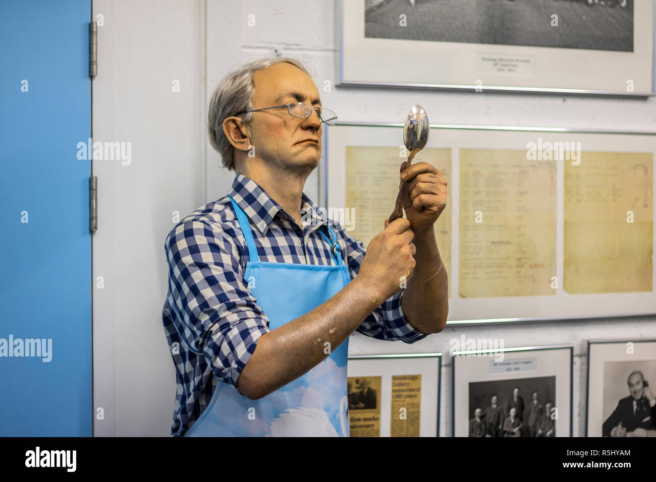 wax statue of a silversmith inspecting, holding a spoon, older man, factory worker, silversmith concept Stock Photo