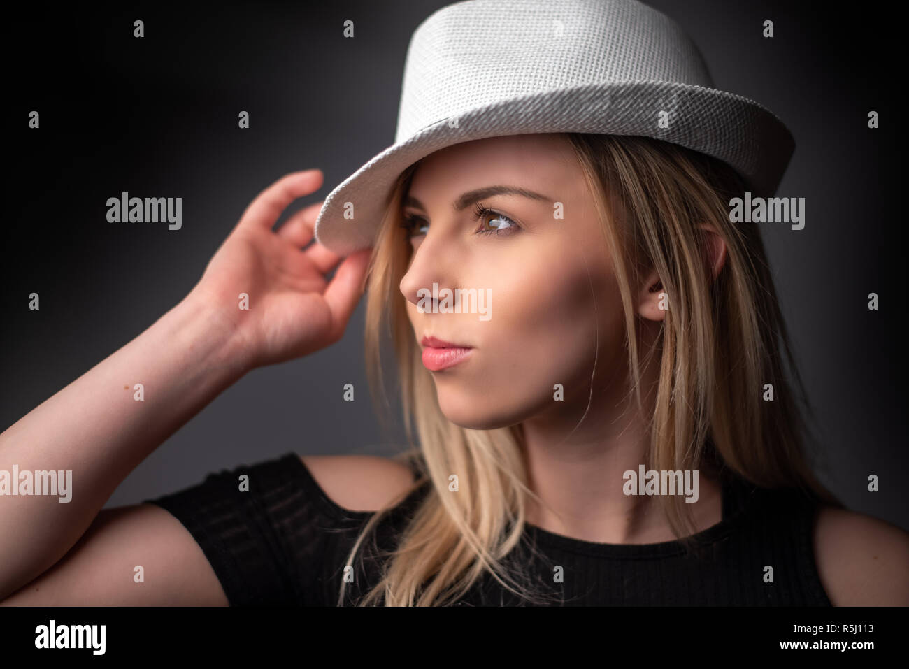 Studio portrait of a young blonde woman wearing a white hat Stock Photo