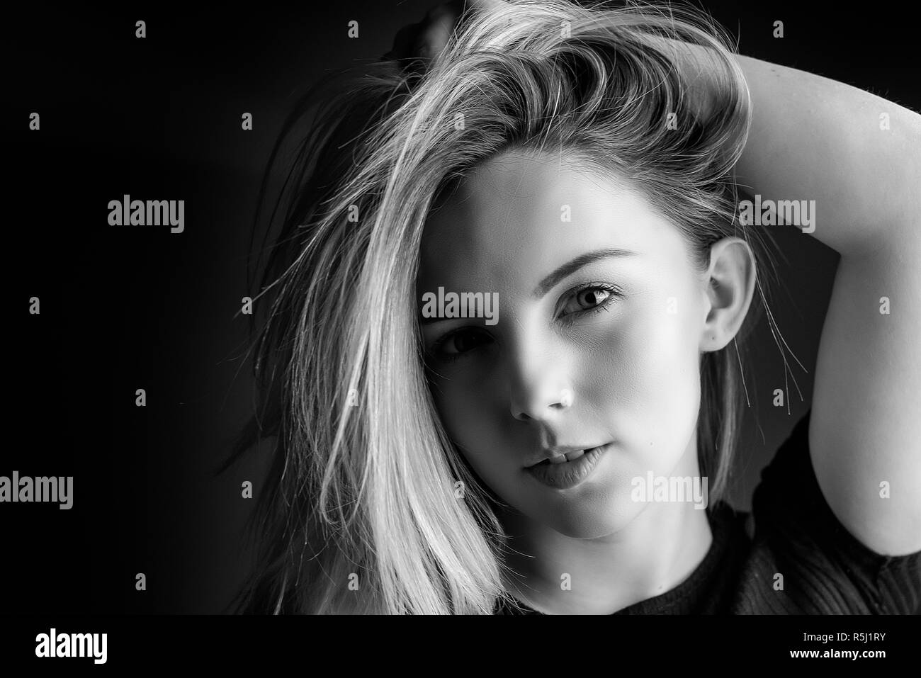 Studio Portrait of a young blonde woman with her hand in her hair Stock Photo