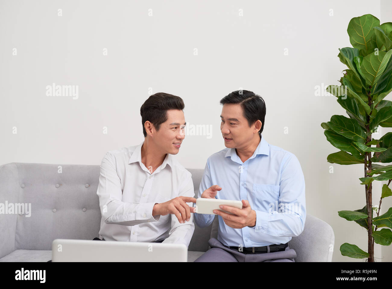 Good mood. Two businessman sitting in front of laptop talking about their plans. Stock Photo