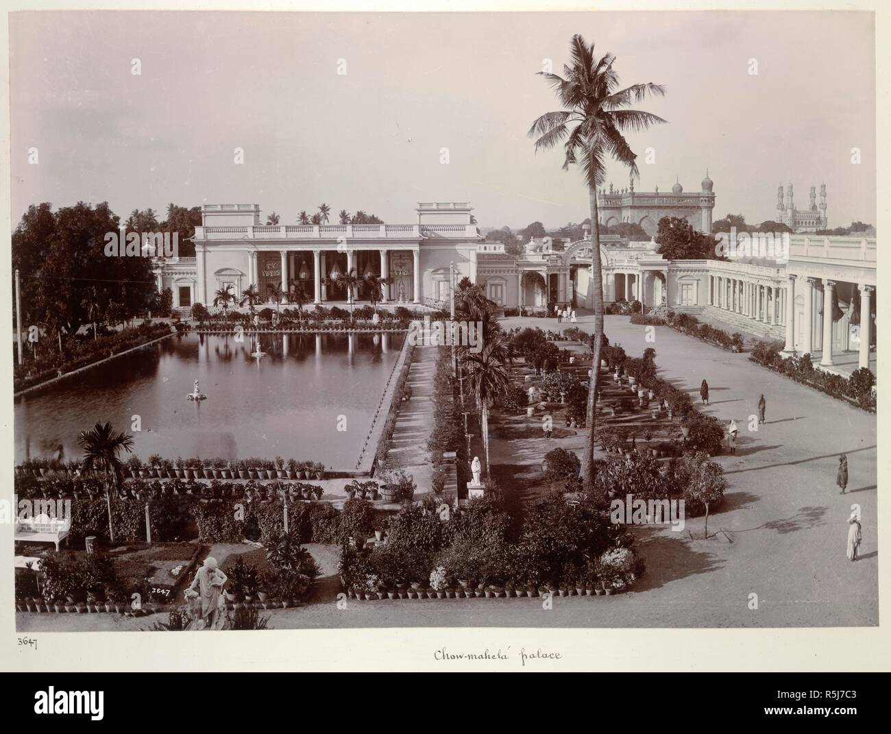 Chow-mahela palace [Hyderabad]. A view looking across the garden and tank towards one of the buildings of the Chaumahalla Palace. The Char Minar visile can be seen in the right background. Curzon Collection: 'Souvenir of the Visit of H.E. Lord Curzon of Kedleston Viceroy of India to H.H. the Nizam's Dominions April 1902'. c. 1902. Photograph. Source: Photo 430/33(41). Language: English. Author: Dayal, Deen. Stock Photo