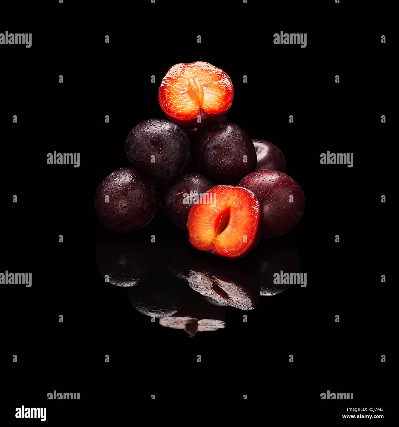 Stack of purple plums isolated on black Stock Photo