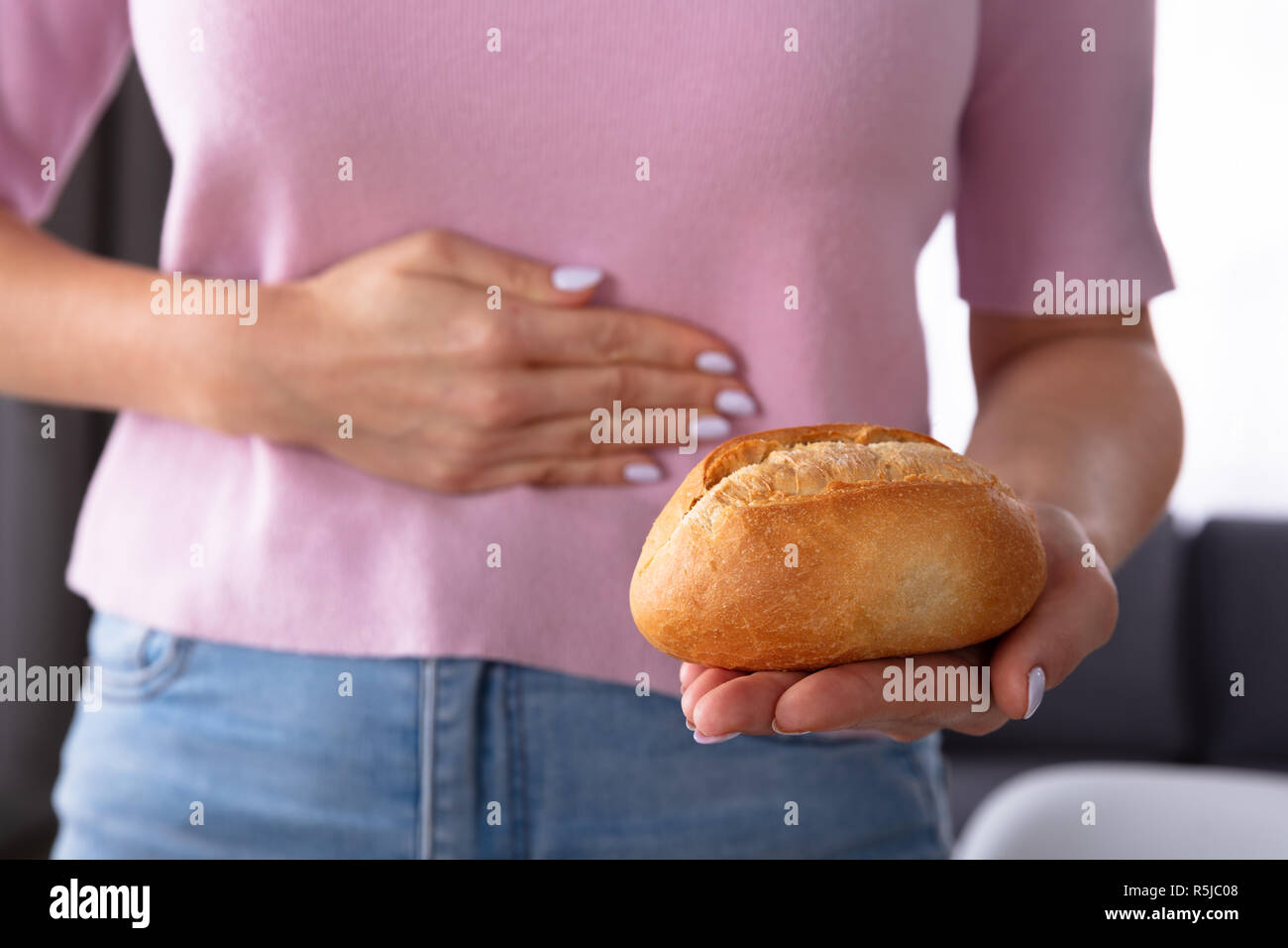 Midsection View Of A Woman Suffering From Stomach Pain Holding Bread