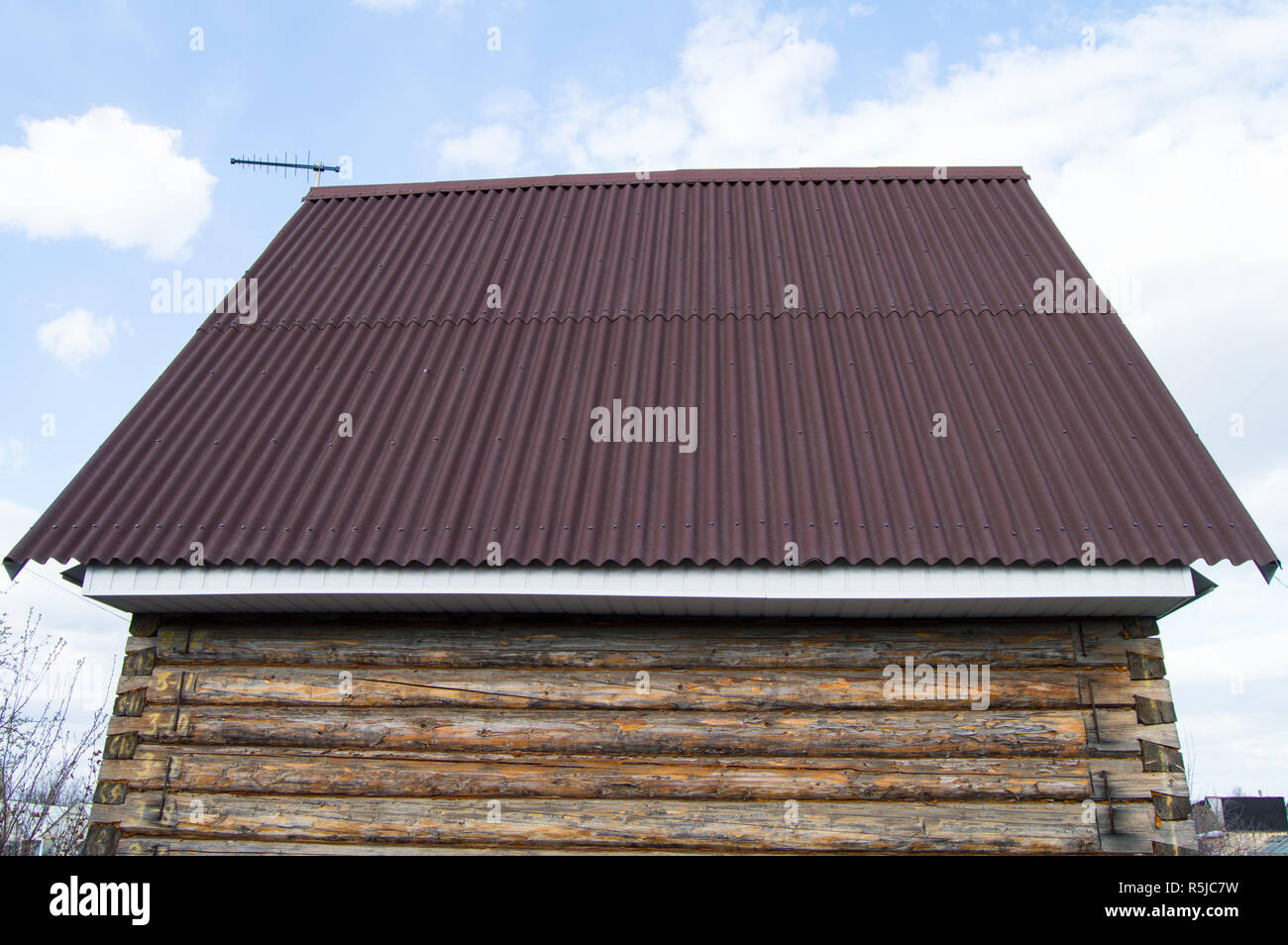 modern construction of the roof with red metal siding to a wooden house in the garden Stock Photo