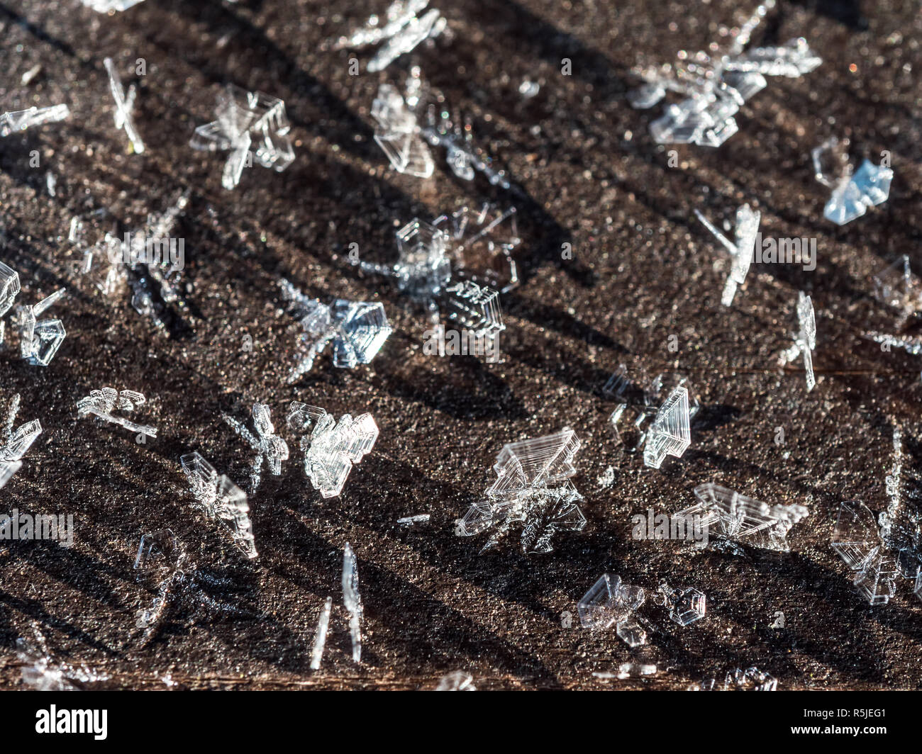 Frost crystals forming beautiful  geometrical shapes on wood surface against black background Stock Photo