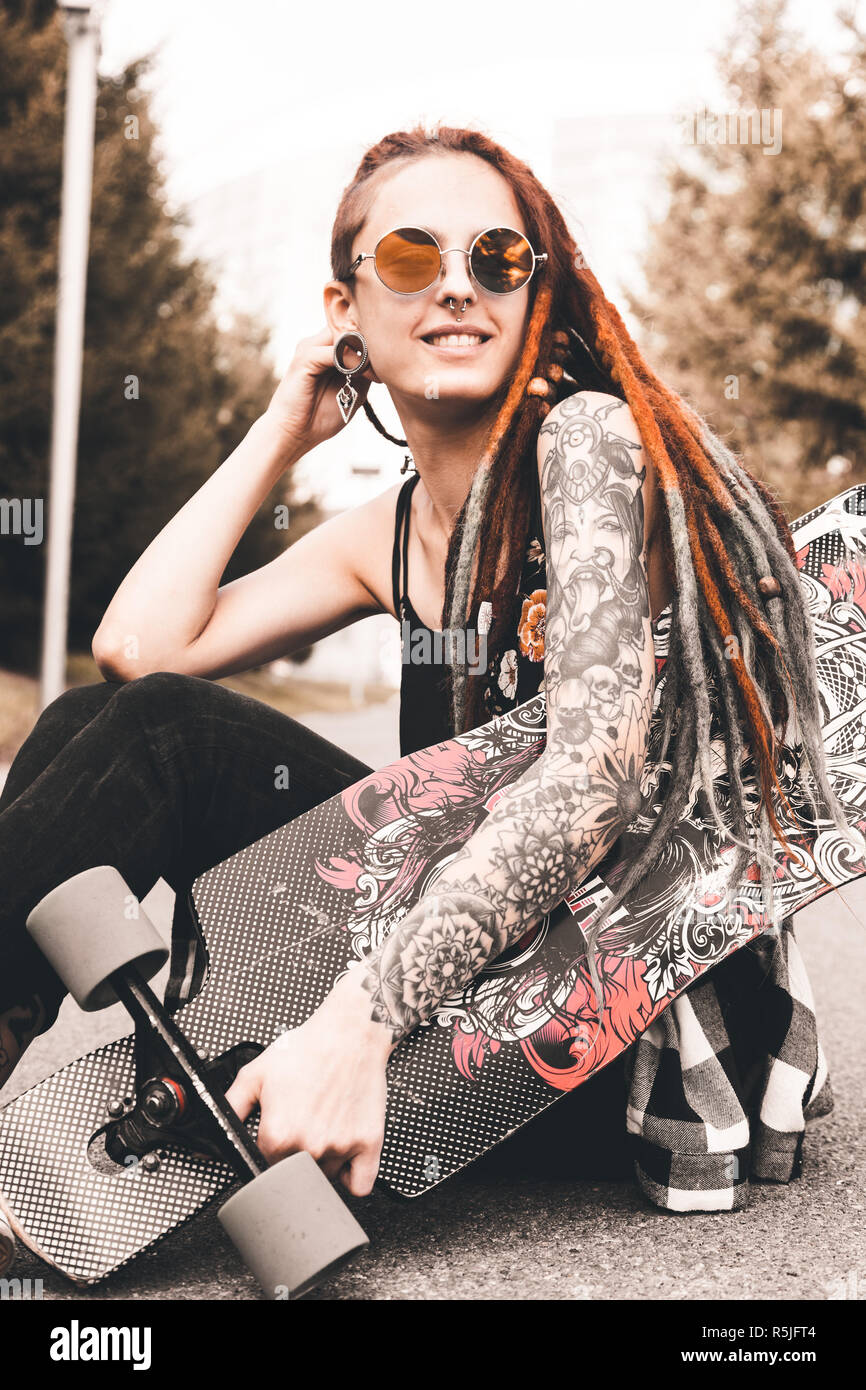 Young Girl With Tattoo And Dreadlocks Sitting In The Park