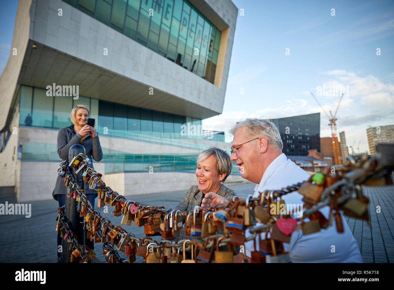 Pier Head Liverpool Waterfront tourists locking padlocks onto railings as a symbol of their love