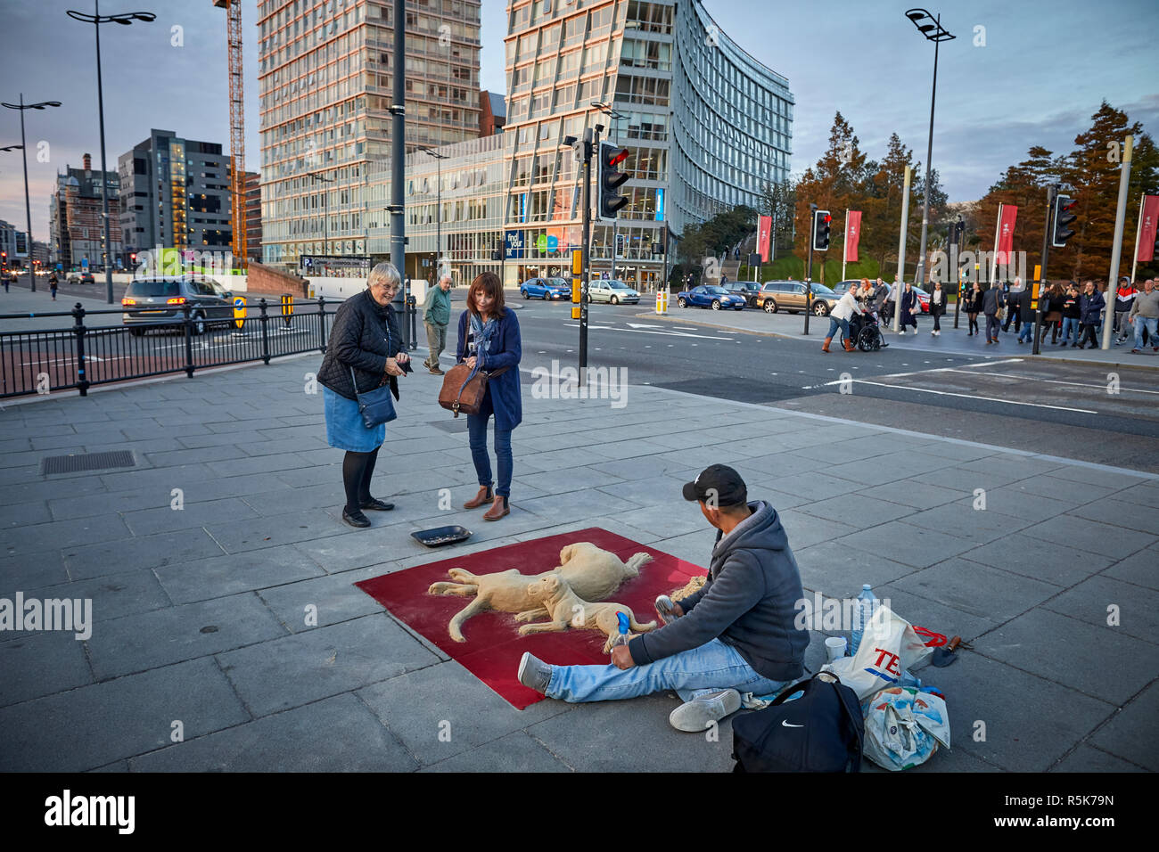 Liverpool Waterfront Albert Docks a man busker  makes sand dog sculpture for donations on the Starnd Stock Photo