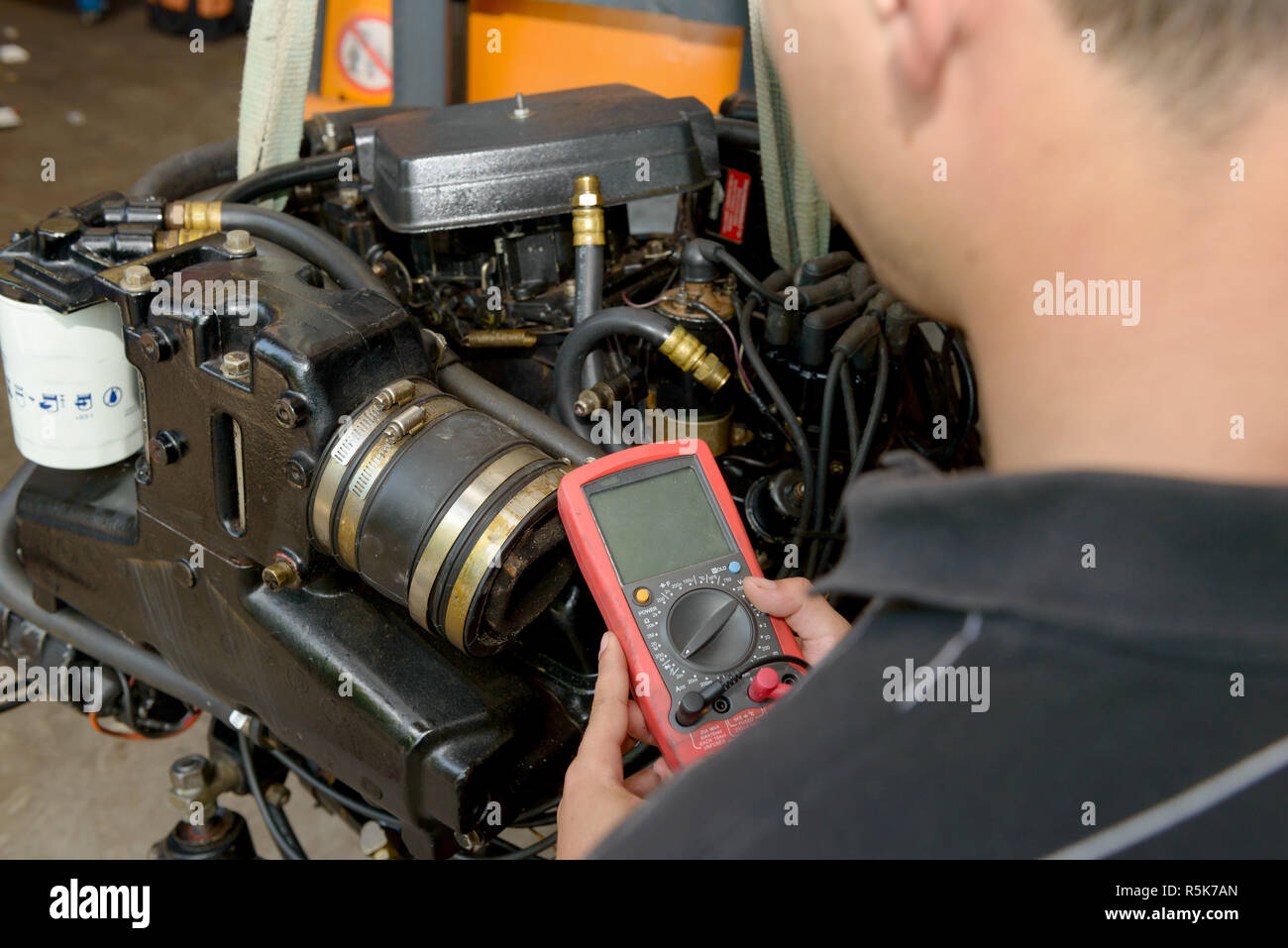 mechanic man with digital multimeter testing ignition coil Stock Photo
