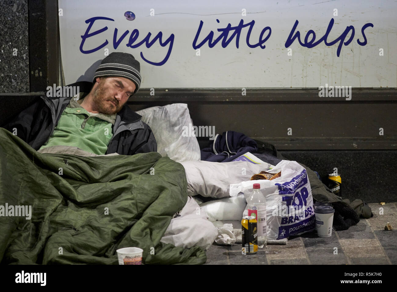 Liverpool city centre sleeping homeless begging man with mess around him as he sleeps, every little helps tesco slogan Stock Photo