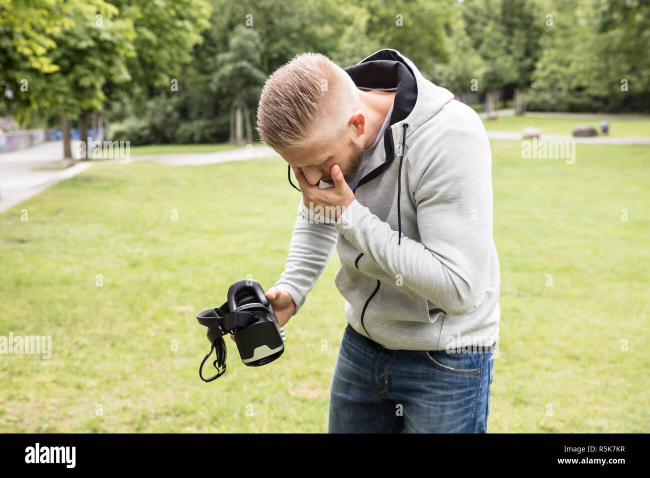 Man With Nausea Holding Virtual Reality Headset Stock Photo