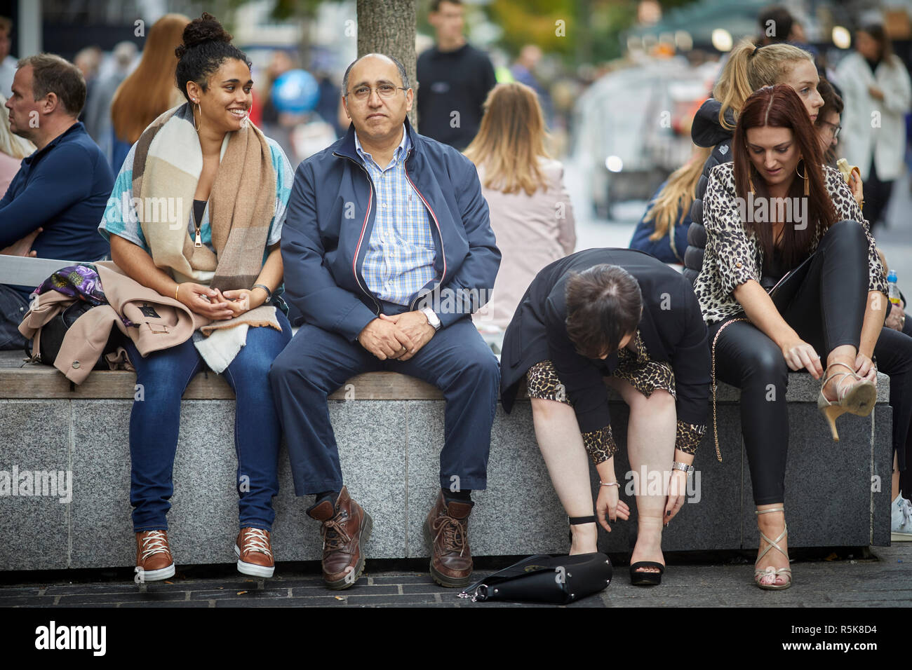 Liverpool city centre people resting on street furniture benches Stock Photo