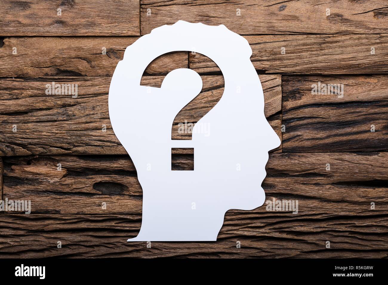 Paper Businessman's Head With Question Mark On Wooden Table Stock Photo