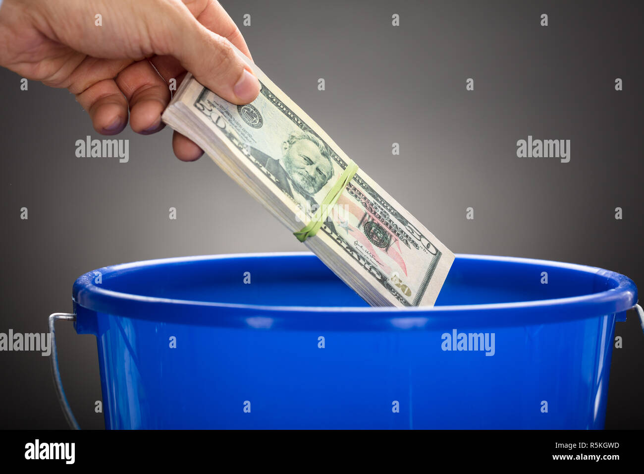 Hand Throwing Us Paper Currency Bundle In Blue Bucket Stock Photo Alamy
