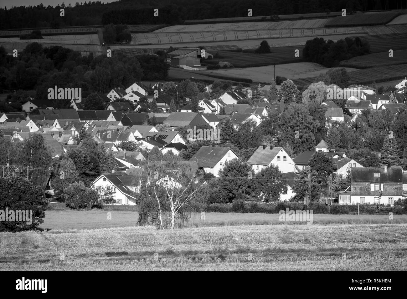 View of the small town of Neustadt (Marburg-Biedenkopf district in Hessen), the suburbs and surrounding agricultural land in the morning sun. Black and white. Stock Photo