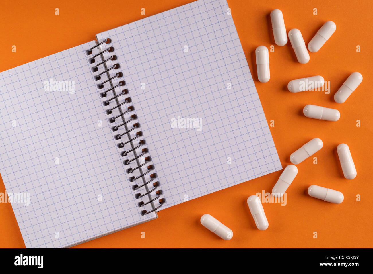 Medicinal medicine capsules and pills around a blank notepad on a ...