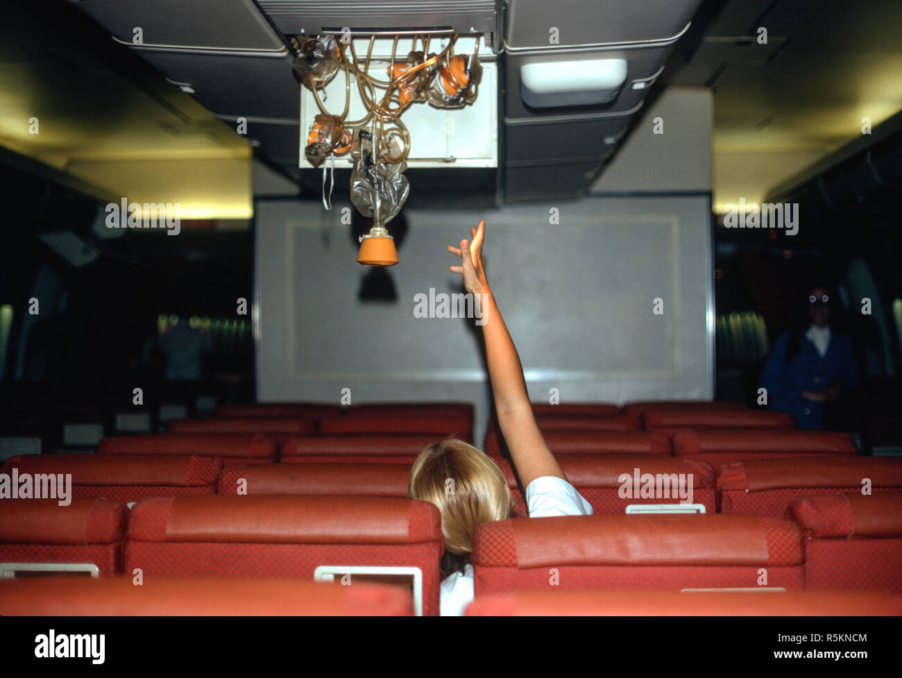 Blond Woman Reaching for a Oxygen Mask in a 747 Commercial Airline, USA Stock Photo
