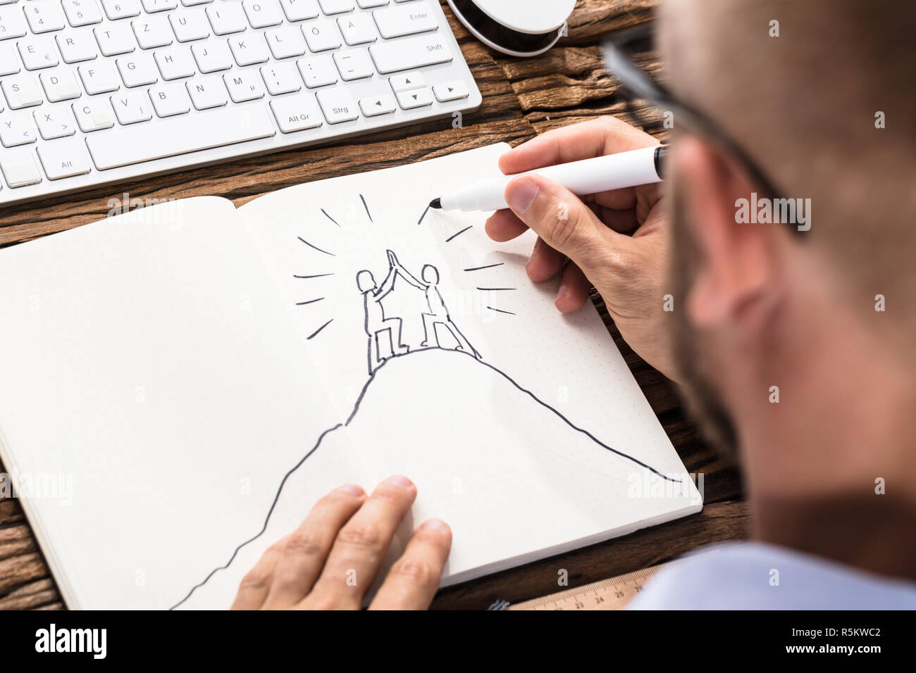 Businessman Drawing The Figures Giving High Five On Notebook Stock Photo