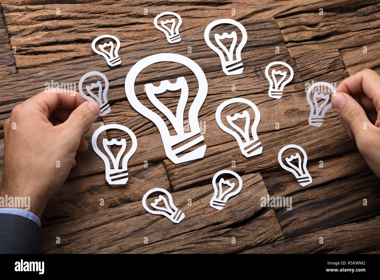 Businessman Arranging Paper Light Bulbs Stock Photo