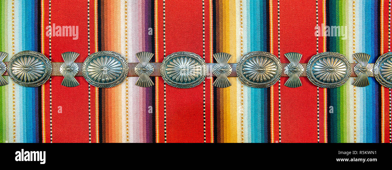 Sterling Silver Native American Concho Belt on Brightly Colored Southwestern Pattern Fabric. Stock Photo