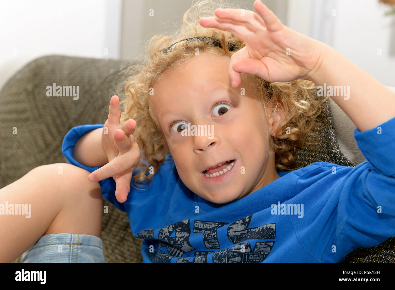 Little Boy With Blond And Curly Hair Making Faces Stock Photo