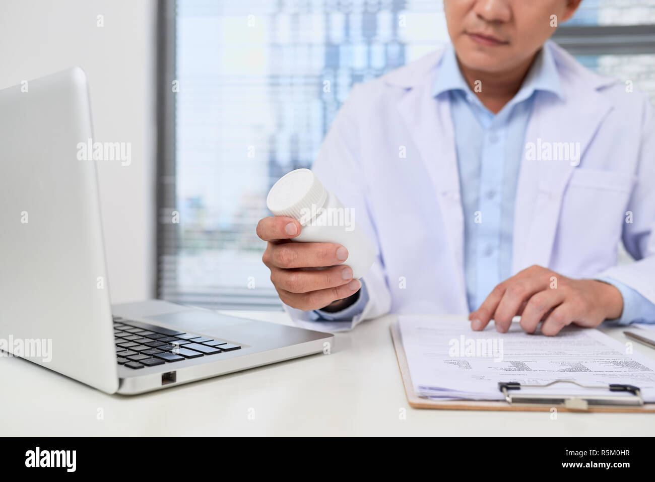 Doctor filling up an history form while consulting to patient and recommend treatment methods and how to rehabilitate. Stock Photo