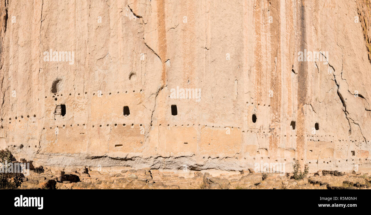 Panorama of abandoned ancient cliff dwellings and caves in a massive cliff face with adobe ruins at the Long House in Bandelier National Monument Stock Photo