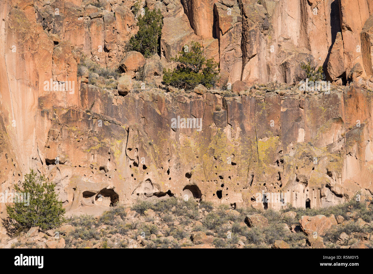 Ancient dwellings and abandoned ruins in a colorful cliff face  in Bandelier National Monument Stock Photo