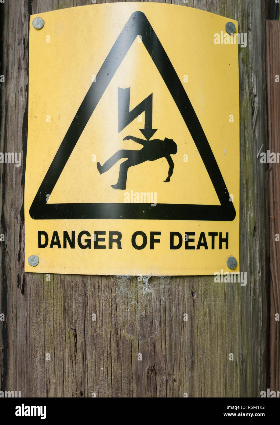 yellow danger of death sign on wooden post Stock Photo