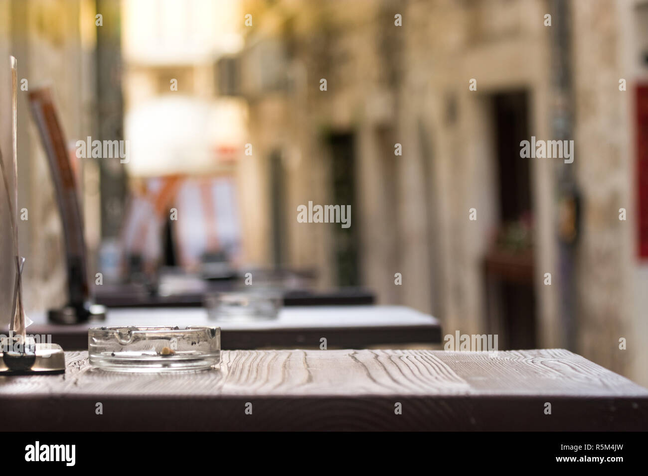 Perspective of a wooden table with an ashtray outside a bar in Split