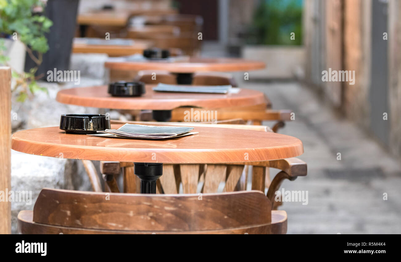 Perspective of wooden tables with an ashtray outside a bar in Split