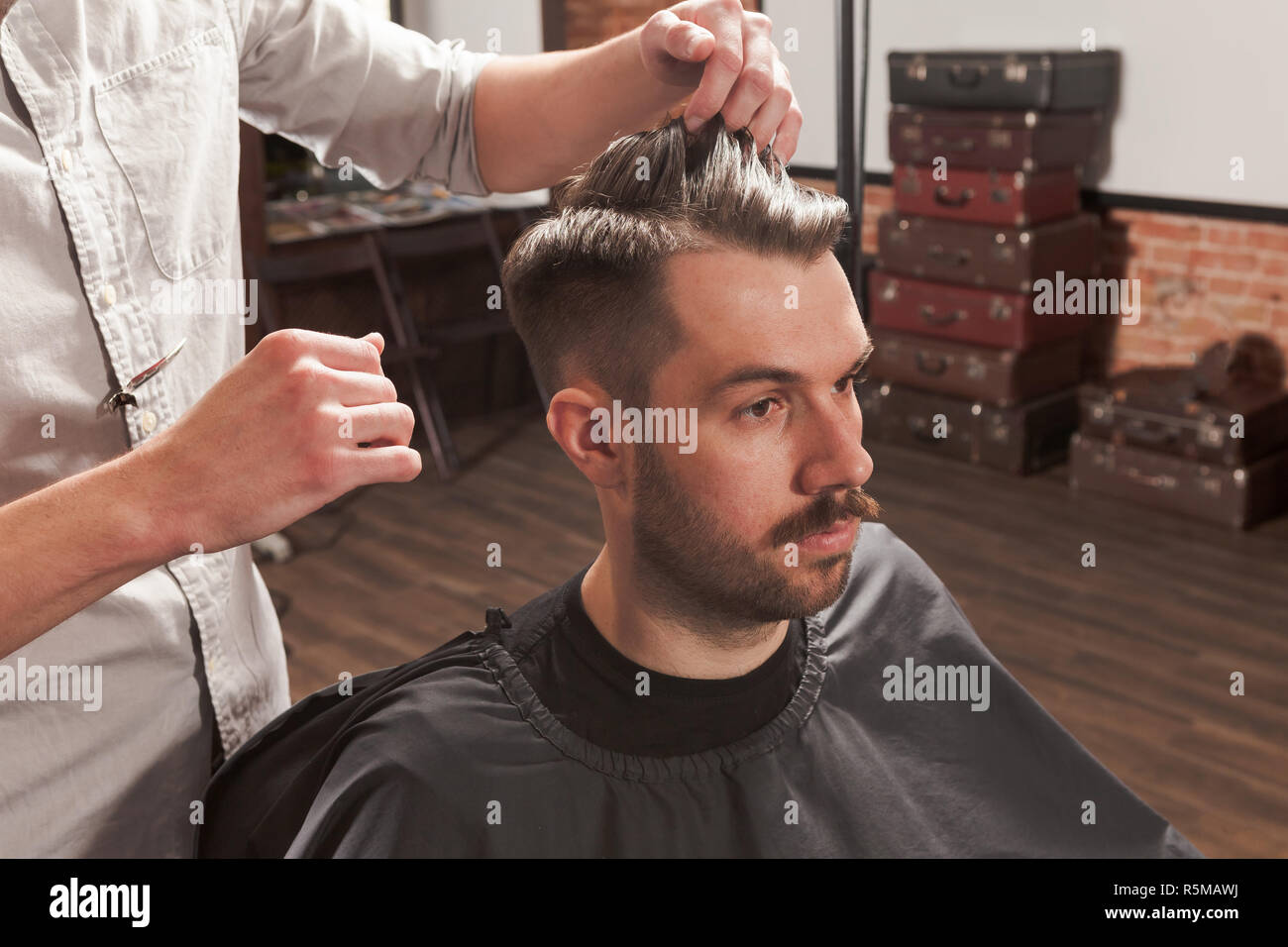 The Hands Of Barber Making Haircut To Young Man In Barbershop