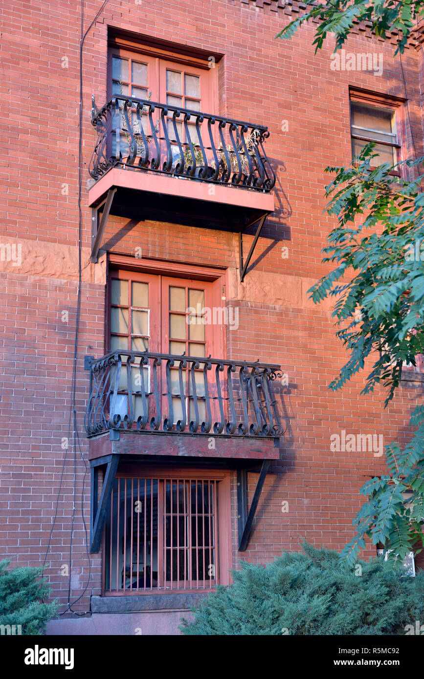 Windows with individual ornate iron balconies in old red brick building, USA Stock Photo