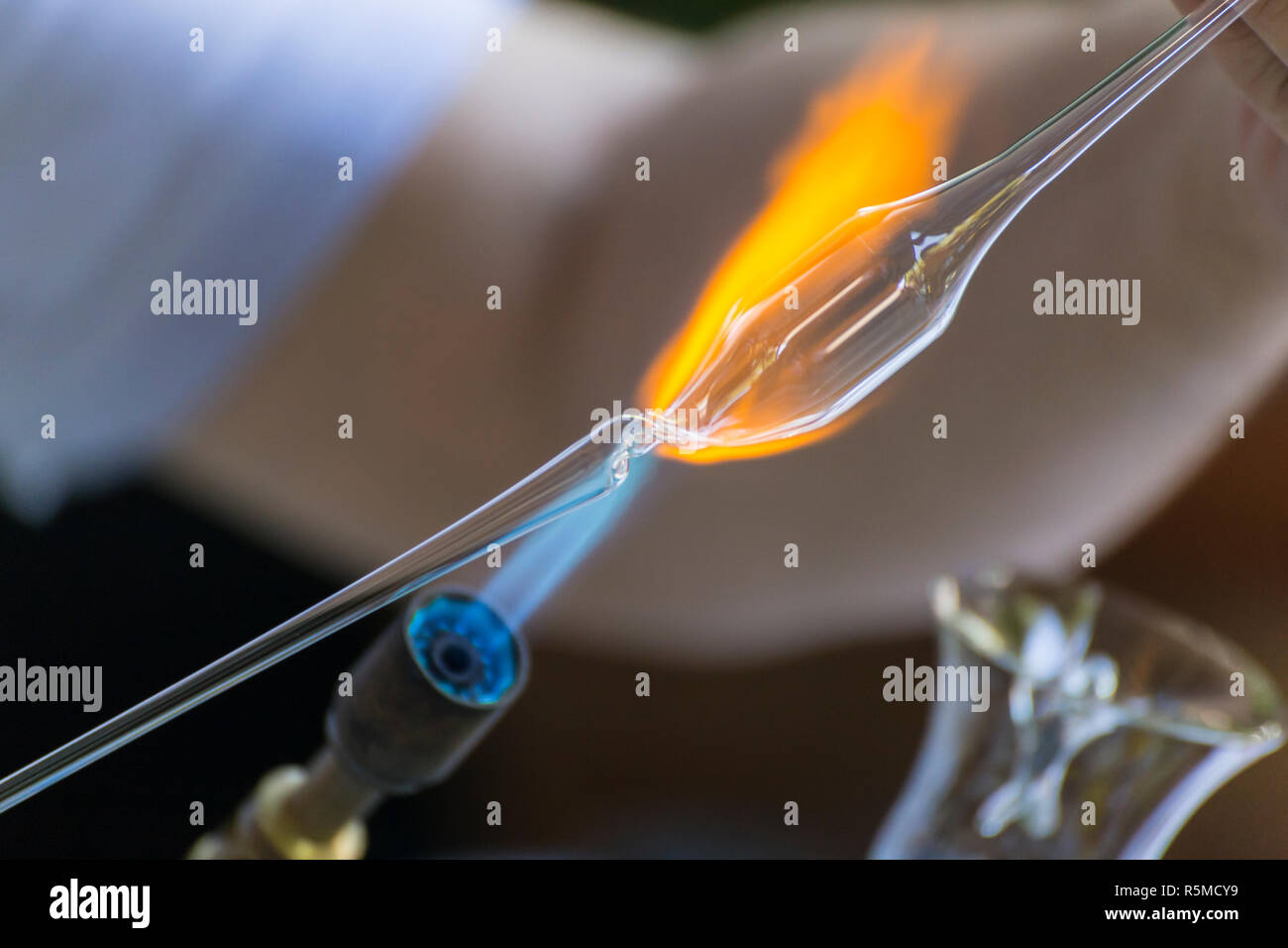 Craftsman melting and shaping a piece of glass on a small blue torch