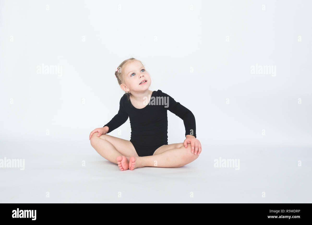 Cute little girl in beautiful black dress sitting on the floor on white ...