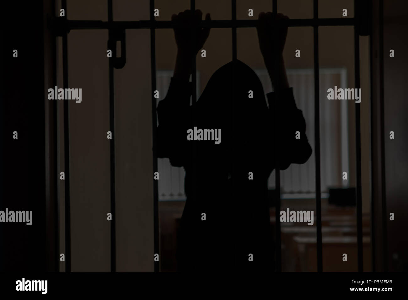 The prisoner behind the bars.Hold with hands on the grids in desperation. Stock Photo