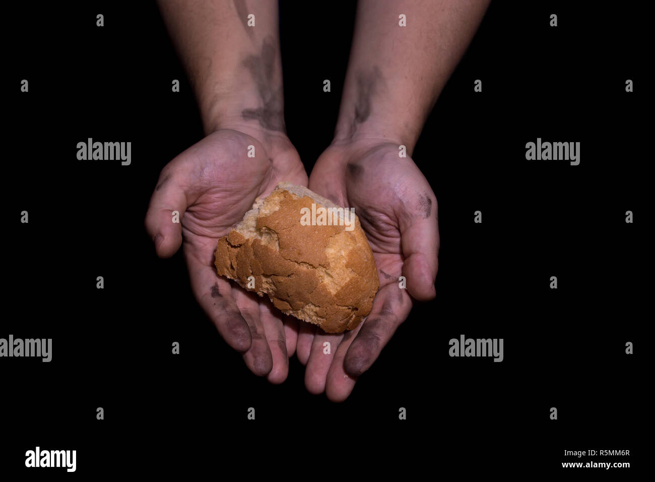 Poverty concept. Hands holding bread isolated on balck background. Stock Photo