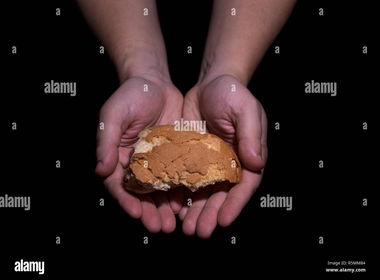 Poverty concept. Hands holding bread isolated on balck background. Stock Photo