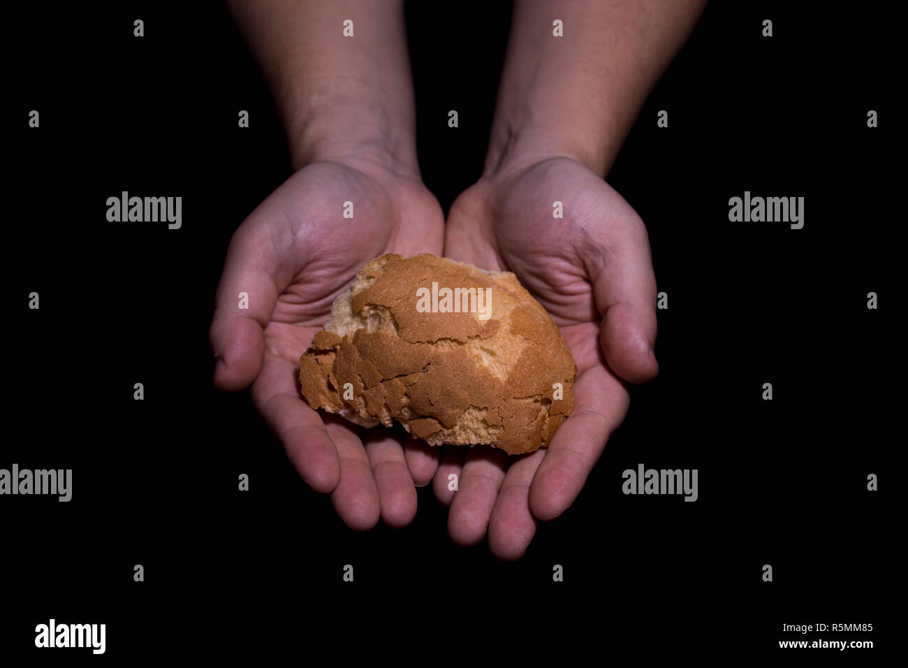 Poverty concept. Hands holding bread isolated on balck background. Stock Photo