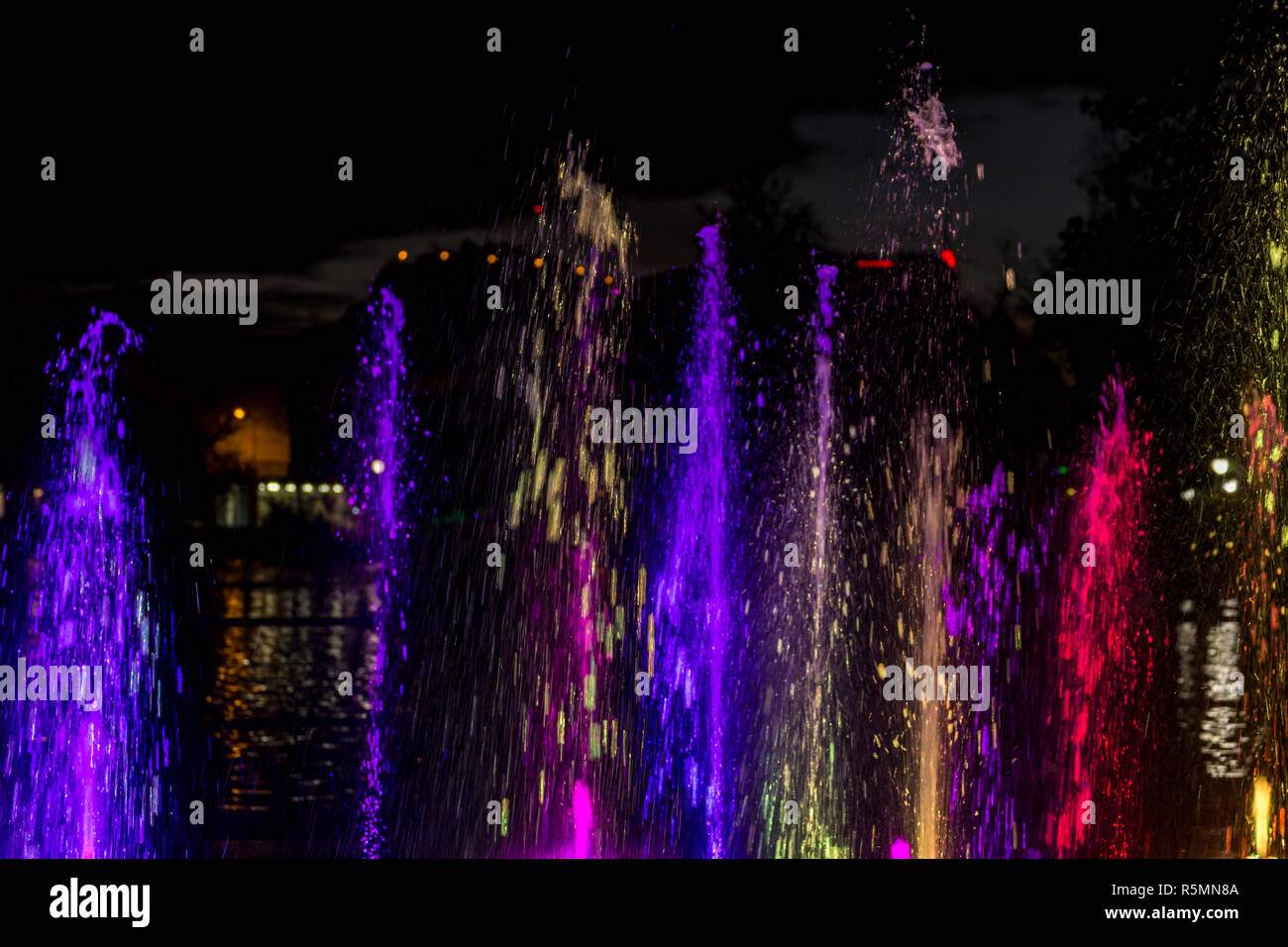 Colorful fountain water spray at night Stock Photo - Alamy