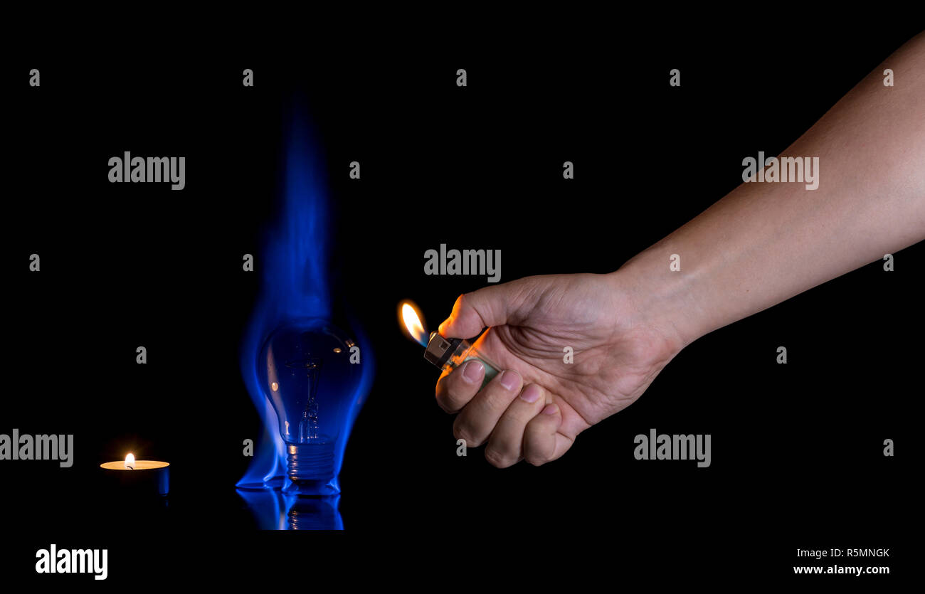 Hand lighting a lightbulb isolated on black background. Wrong usage concept. Stock Photo