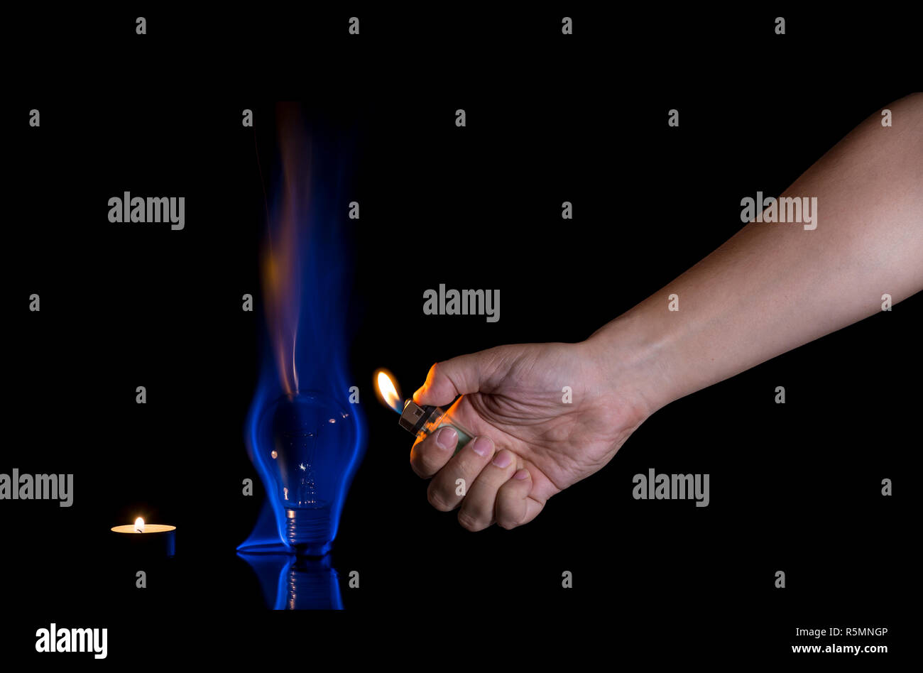 Hand lighting a lightbulb isolated on black background. Wrong usage concept. Stock Photo
