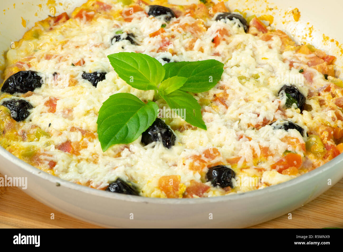 Menemen with tomatoes, egg, green pepper, olives, halloumi cheese, basil, thyme and mint Stock Photo