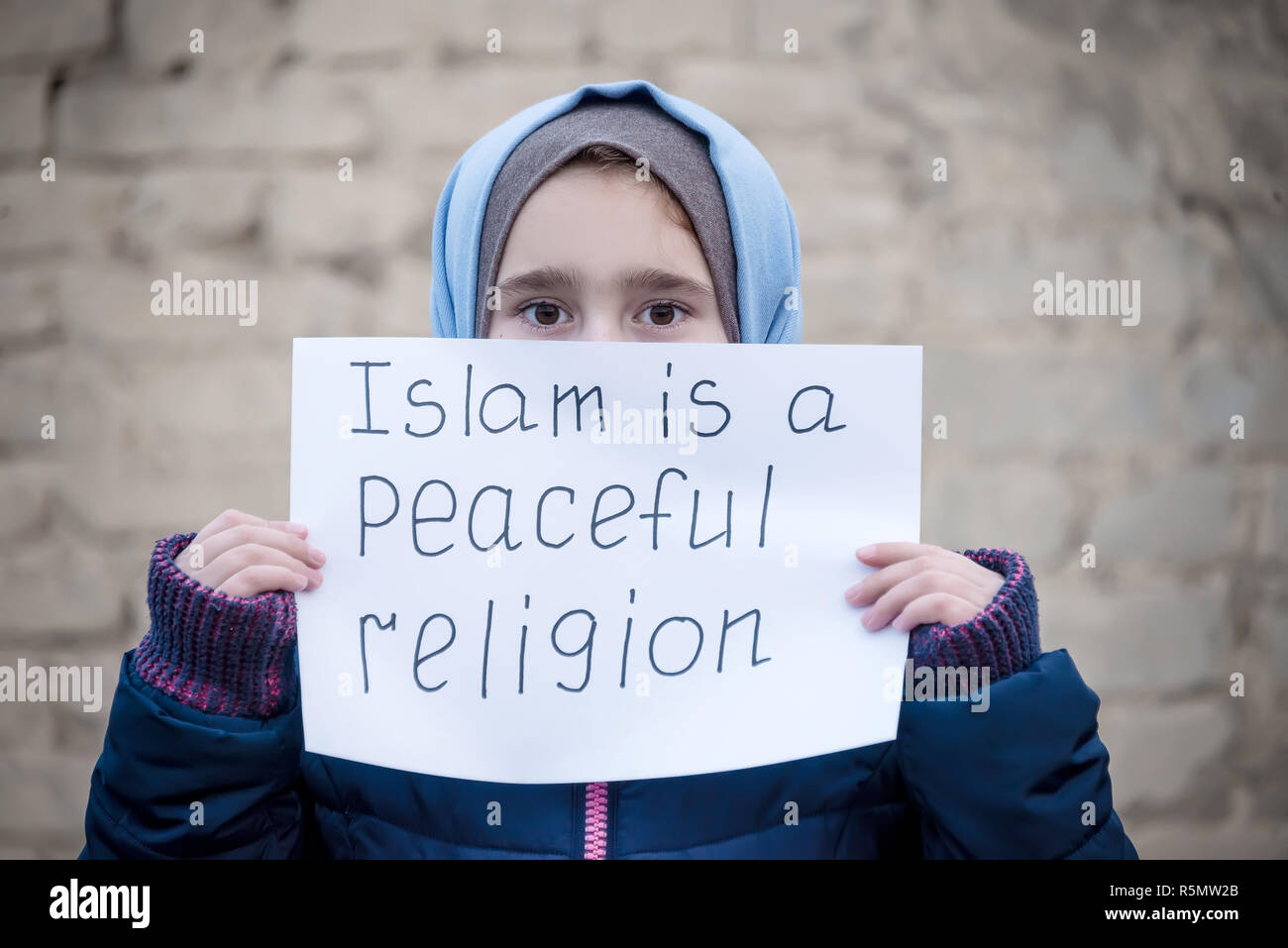 refugee girl with an inscription on a white sheet 'Islam is a peaceful religion' Stock Photo