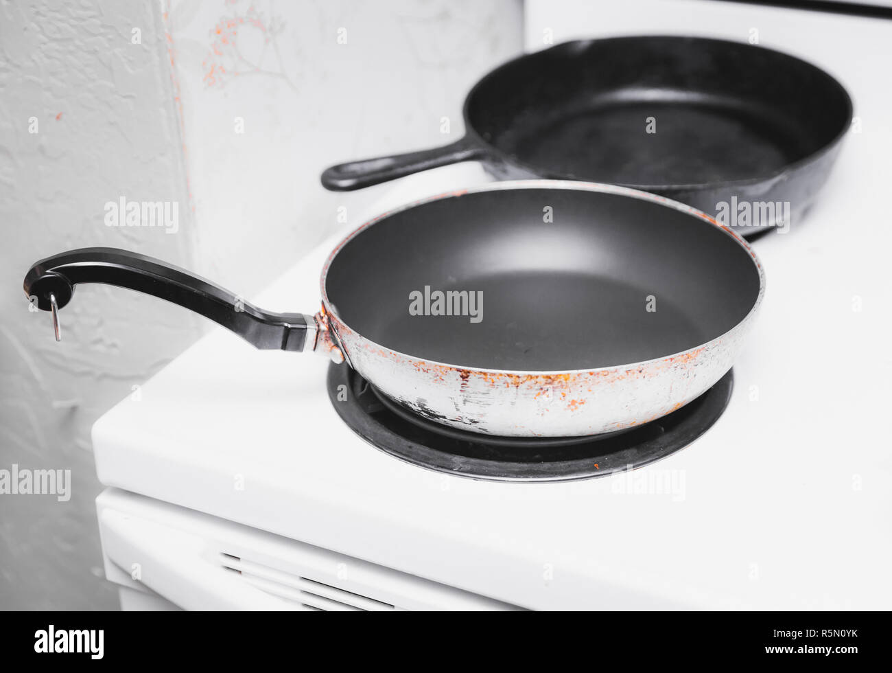Nonstick pan and cast iron pan on  a white oven with electric coil burners. Stock Photo