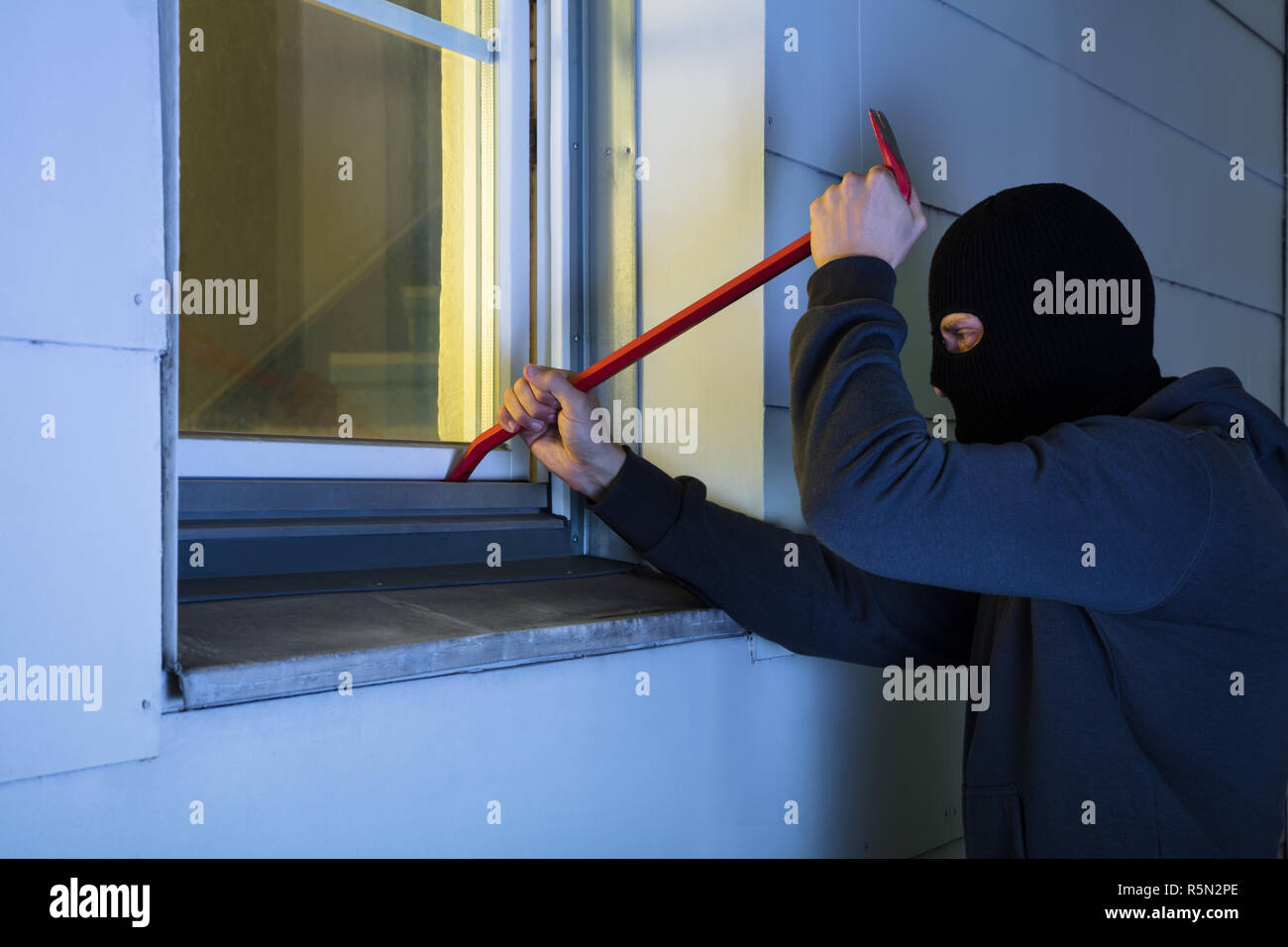 Burglar Using Crowbar To Break Into A House Stock Photo